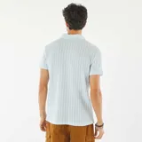 Remera polo celeste de punto gofrado con cuello clásico y mangas cortas.