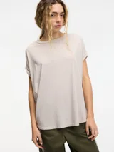 Remera color beige de corte amplio, cuello redondo y mangas cortas con dobladillo.