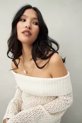 Sweater color crema, tejido de punto calado, con escote off-shoulder y mangas largas acampanadas.