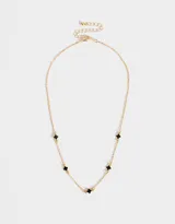 Collar corto dorado con cadena de eslabones y dijes de flores esmaltadas negras.