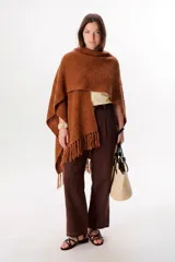 Ruana color tostado de tejido de punto con diseño de espiga y flecos en el borde inferior.