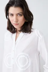 Blusa blanca con cuello mao y mangas 3/4. Presenta apliques circulares bordados en el frente.