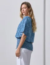 Blusa celeste con estampado floral, escote en V y ruedo smock.