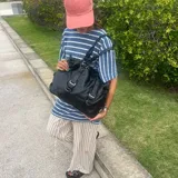 Bolso tipo tote negro de eco cuero con correa de hombro.
