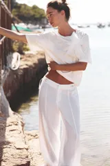 Camiseta blanca de algodón con cuello redondo, manga corta y detalle de flor de organza con strass en el frente.
