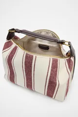 Bolso de mano tipo city, confeccionado en tejido con estampado de rayas verticales en tonos crudo y bordó. Tiene doble correa de hombro extraíble en contraste de tejidos, detalles metálicos y cierre mediante cremallera.