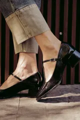 Zapatos de charol negro con diseño tipo T-bar, taco bajo cuadrado y punta redondeada.