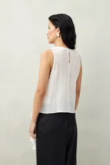 Top blanco de tencel sin mangas, de corte asimétrico, con volados en diagonal.