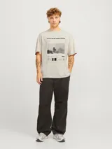 Remera color crema de manga corta y cuello redondo con estampado de una foto enmarcada con texto y c
código de barras. Corte holgado.
