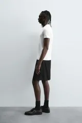 Bermuda negra de corte relajado, confeccionada en tejido satinado de viscosa. Presenta cintura elástica ajustable con cordón interior, bolsillos frontales y un bolsillo trasero de plastrón.