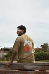 Remera gris con efecto gastado, de manga corta y corte holgado. Estampa en el pecho con un sol, una ola y la frase 'Life is Better'.