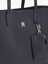 Bolso tipo tote Tommy Hilfiger color azul marino con diseño de monograma TH en relieve. Incluye monedero extraíble con cremallera y cierre magnético. Tiene doble asa superior, dos compartimentos principales y un compartimento interior con cremallera.