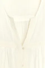 Blusa color crema de cuello redondo con escote pico y manga ancha por debajo del codo. Detalle de acabados con bordados. Cierre frontal con botones.