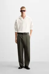 Pantalón verde oliva de corte amplio con pliegues en la parte delantera, bolsillos laterales y traseros de ojal.