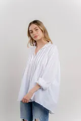 Camisa blanca de algodón con diseño oversize, cuello camisero y pliegues frontales que le dan textura.