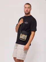 Bandolera negra de poliéster con correa ajustable y logo estampado.