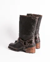 Bota de cuero color marrón oscuro, de caña media, con hebilla y tachas decorativas.