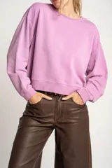 Sweater lila de algodón, corte holgado, con cuello redondo y mangas largas.