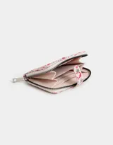 Billetera de cuerina color blanco con estampado de cerezas, frutillas y flores. Tiene cierre circundante y solapa con broche a presión. Cuenta con compartimentos para tarjetas y billetes.