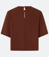 Blusa color ladrillo de mangas cortas confeccionada en crepé texturizado, con cuello redondo y abertura en la espalda. Corte recto y holgado.
