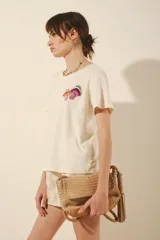 Remera color crema de manga corta con cuello redondo y estampado de hongos bordados en el frente.