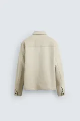 Sobrecamisa color beige de tejido efecto ante, corte regular fit, con cuello solapa, manga larga con puños abotonados, bolsillos de parche con solapa en el pecho y bolsillos de ojal en la cadera.