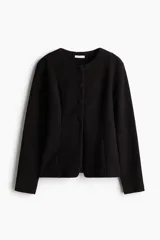 Saco negro en tejido bouclé con cuello redondo, botones forrados hasta la cintura y corte acampanado en la parte inferior.