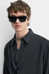 Camisa negra relaxed fit confeccionada en tejido fluido con mezcla de viscosa. Tiene cuello solapa, manga larga con puño abotonado y cierre frontal con botones.