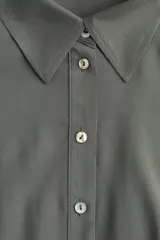 Vestido midi color verde oliva con cuello camisero, botonadura frontal y mangas raglán cortas. Tiene elástico fino en la parte posterior de la cintura, frunces adelante y atrás, y cinturón extraíble para atar.