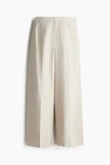 Pantalón de vestir color beige claro, de corte amplio y largo cropped. Confeccionado en tejido de mezcla de lino y viscosa, de tiro alto con cierre, botón oculto y corchete.