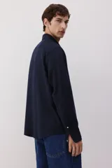 Camisa de hombre de lino color azul marino, de corte regular, con cuello inglés, tapeta clásica, mangas largas con puños abotonados y bajo redondeado.