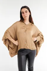 Camisa color beige de satén con corte holgado, cuello camisero y mangas largas con puños abotonados.