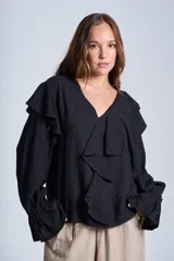 Blusa negra de manga larga con escote en V y volados en el frente y puños elásticos.