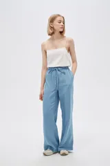Pantalón de jean celeste, de corte ancho, con cintura elástica y cordón ajustable.