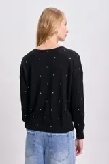 Buzo negro de punto fino con cuello redondo y tachas plateadas en forma de estrella.