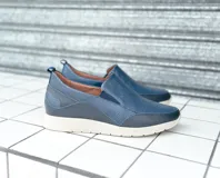 Zapato tipo mocasín color azul marino, con elástico en la abertura y suela color crema.