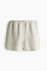 Short color crema de lino y viscosa, con cintura elástica ajustable con cordón, bolsillos laterales y aberturas laterales en el ruedo.