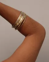 Brazalete rígido dorado con textura irregular.