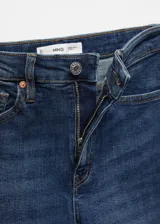 Jeans de tiro alto color azul oscuro, corte skinny, cinco bolsillos, cierre con cremallera y botón, confeccionados en tejido de algodón estilo tejano vaquero.