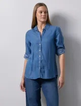 Camisa celeste de tencel con cuello con solapa, escote en V, abertura central con botones y mangas 3/4 regulables con presilla y botón.