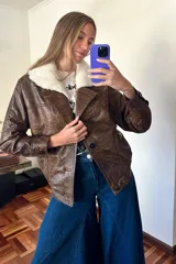 Campera bomber de cuero marrón veteado con cuello desmontable de corderito crudo y detalle de pasamanería en las mangas.