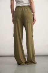 Pantalón cargo color verde oliva, de corte ancho, con bolsillos laterales con solapa y cintura con cordón ajustable.