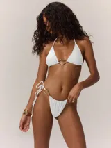 Conjunto de bikini blanco con corpiño triangular con detalle de argolla dorada y bombacha con tiras ajustables y detalle de argolla dorada.