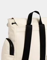 Mochila color beige con detalles en negro. Tiene solapa con tira de ajuste y broche, correas regulables, manija superior, bolsillo frontal con cierre y puller de cordón y goma, bolsillos laterales con cierres y pullers de cordón y goma, y tag de goma.