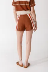 Short tejido en jersey color marrón con detalles de rayas verticales en color crema y ribete naranja.