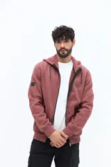 Campera de felpa color rosado oscuro con capucha ajustable mediante cordones y bolsillos laterales con cierre.