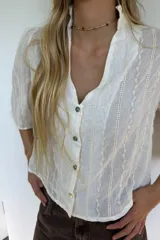Blusa blanca de algodón liviano con bordado vertical, manga 3/4, cuello mao y cierre frontal con botones.
