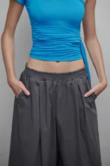 Bermuda gris de corte ancho, con pretina elástica, tiro bajo, bolsillos laterales y cierre lateral.