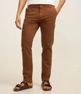 Pantalón de vestir color marrón, de corte recto, con bolsillos laterales y traseros. Se ajusta a la cintura con cinturón de cuero marrón.
