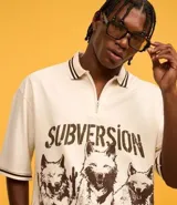 Camisa oversized color crema con cuello polo y cierre de cremallera. Estampado frontal con la palabra "Subversion" y tres lobos.